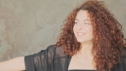 Wall Mural - Cute cheerful young redhead woman in silk robe opening the curtains and looking at the window at home in the morning