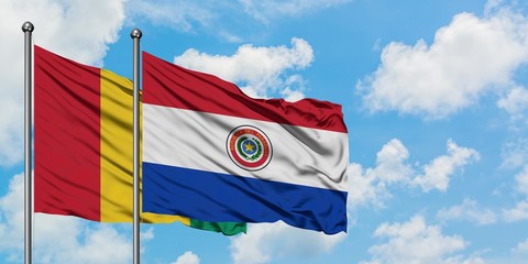 Guinea and Paraguay flag waving in the wind against white cloudy blue sky together. Diplomacy concept, international relations.