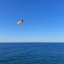 A Man With A Parachute Flies Over The Sea.