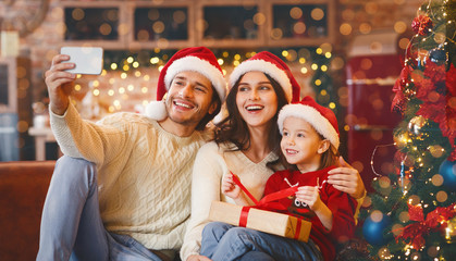 Young happy family of three taking selfie on Christmas eve