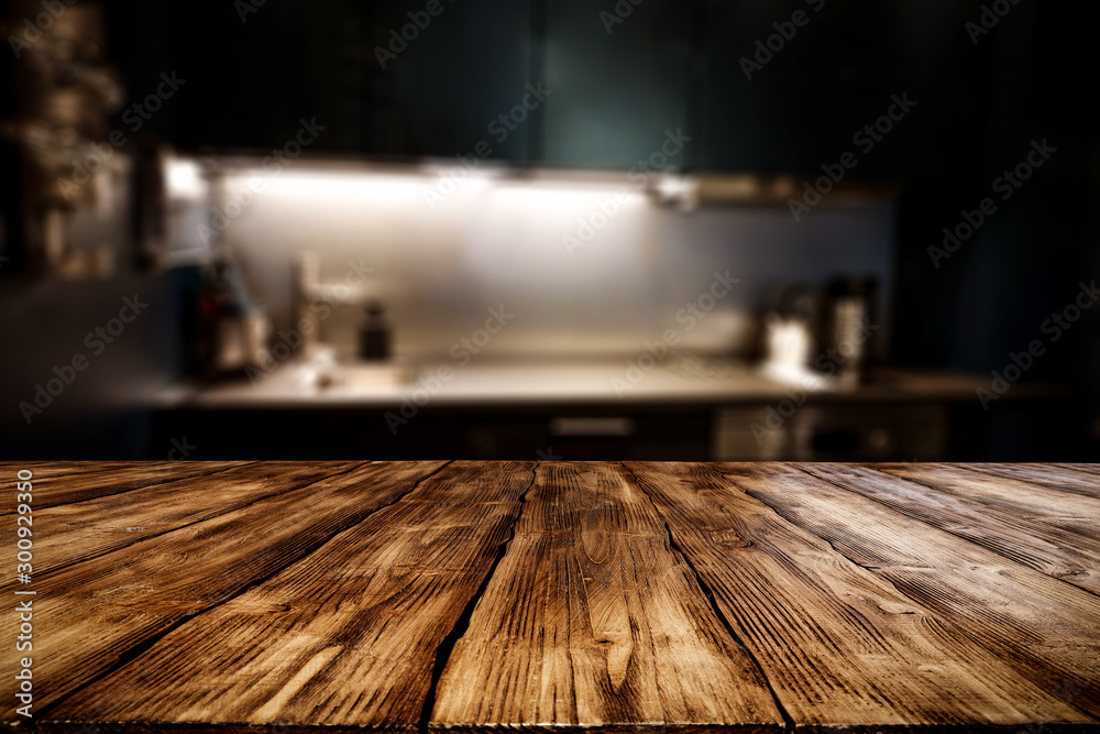 Wooden table background of free space for your decoration and blurred background of kitchen. Copy space.Dark mood interior. Kitchen furniture.  - obrazy, fototapety, plakaty 