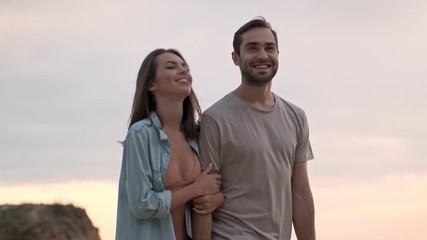 Poster - Cute cheerful young lovely couple smiling while walking outdoors at the seaside