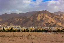 Middle East Poor Arabian Outskirts City District With A Lot Clay Small Houses, Sand Dirt Foreground And Desert Mountain Background 