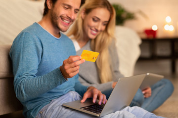 Couple Ordering Shopping Online On Laptop Sitting On Floor Indoor