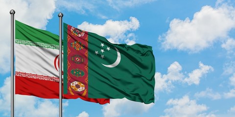 Iran and Turkmenistan flag waving in the wind against white cloudy blue sky together. Diplomacy concept, international relations.