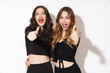 © Drobot Dean - Image of two young women in black outfit smiling and showing thumbs up