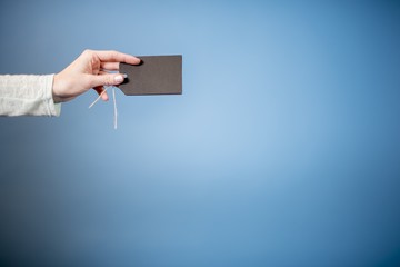 Sticker - Closeup shot of a female holding a blank tag with a blue background - great for writing text