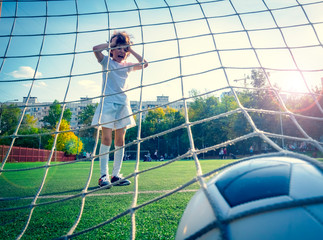 Wall Mural - Young boy or kid plays soccer or football sports for exercise and activity. View from behind the goal nets. selective focus