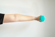 A Close-up Image Of The Left Hand And Arm Of A Woman Lifting Dumbbells Weighs 1 Kilogram In Parallel With The Floor On A White Background.