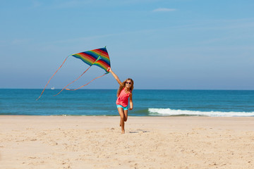 Wall Mural - Little girl run with color rainbow kite on a beach