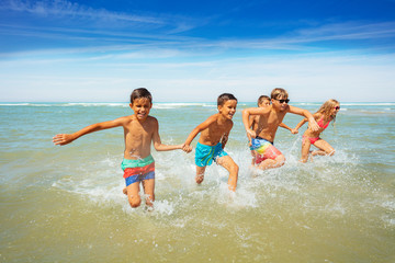 Canvas Print - Many boys and girls run in ocean waves on a beach