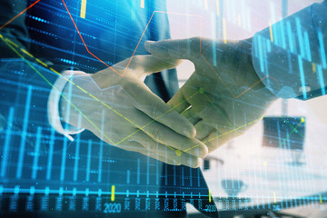 Multi exposure of financial graph on office background with two businessmen handshake. Concept of success in business