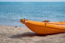 Two Colorful Orange Kayaks On A Sandy Beach Ready For Paddlers In Sunny Day. Several Orange Recreational Boats On The Sand. Active Tourism And Water Recreation.