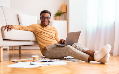 Poster - Afro Man Working On Laptop Sitting On Floor At Home