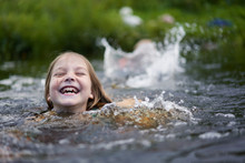 Girl Clumsily Swims In A Small Pond Near The Shore.