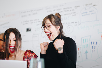 Candid moment, portrait of happy businesswoman celebrating the success of group project in the office, looking at laptop screen. Teamwork  success concepts.