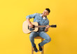 © Pixel-Shot - Handsome man playing guitar on color background