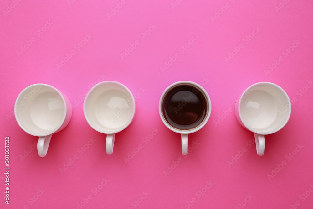 One cup of coffee among empty ones on color background. Concept of uniqueness - obrazy, fototapety, plakaty 