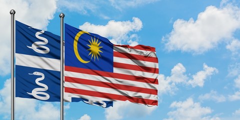 Martinique and Malaysia flag waving in the wind against white cloudy blue sky together. Diplomacy concept, international relations.