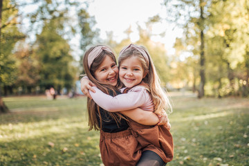 two beautiful child sisters hugging in the park on a sunny day, portrait.