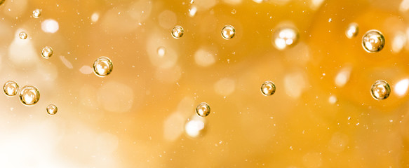 Wall Mural - Bubbles of air on the smooth surface of golden water as an abstract background