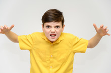 Concept Boy Teenager Shows Imitates The Behavior Of Heroes From Different Movies. Portrait Of A Child On A White Background In A Yellow Shirt. Standing In Front Of The Camera In Poses With Emotions.