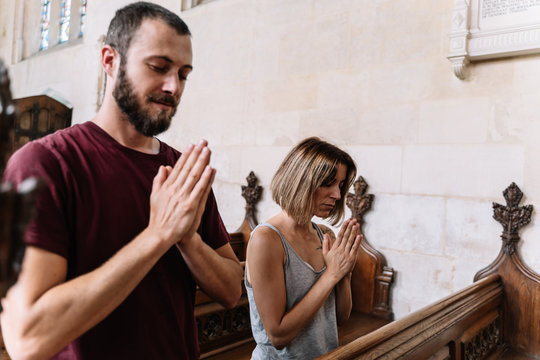 Stock photo of a young couple praying in a church