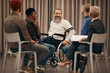 © AnnaStills - Happy senior disabled man sitting in wheelchair and talking to the young people who sitting on chairs in circle during therapy lesson