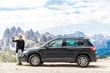 © F8  \ Suport Ukraine - Young man standing near his car on the mountains top and taking selfie on beauty landscape background