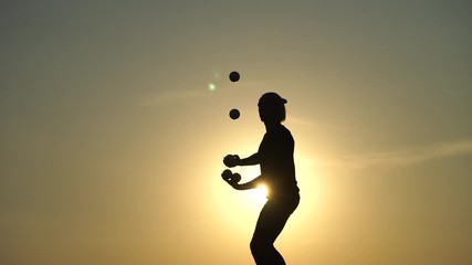 Wall Mural - Circus artist juggling with balls on colorful sunset