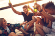 © Zoran Zeremski - Group of friends enjoying a day at the lake. They sitting on pier talking, laughing and drinking beers.