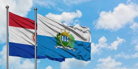 Paraguay and San Marino flag waving in the wind against white cloudy blue sky together. Diplomacy concept, international relations.