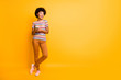 © deagreez - Full length body size photo of cool nice sweet millennial youngster standing confidently with legs crossed looking into empty space holding telephone with hands isolated over vivid color background