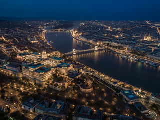 Wall Mural - Budapest, Hungary - Aerial drone view of the illuminated Buda Castle Royal Palace at blue hour. Szechenyi Chain Bridge, River Danube, St. Stephen's Basilica and Parliament of Hungary at background