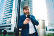 © BullRun - Caucasian professional expert holding cellphone device in hand and pondering on accounting information from website during time in financial district,bearded boss thinking with smartphone for chatting