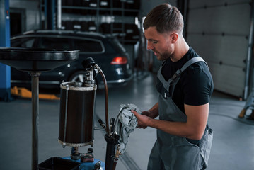 Serviceman cleans instruments. Male mechanic use special device to repair broken automobile in garage