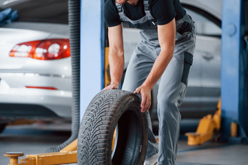 Wall Mural - Order in execution. Mechanic holds a tire at the repair garage. Replacement of winter and summer tires