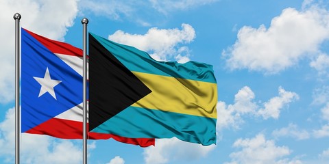 Puerto Rico and Bahamas flag waving in the wind against white cloudy blue sky together. Diplomacy concept, international relations.