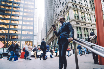 Wall Mural - Businessman in crowded street with smartphone in hand