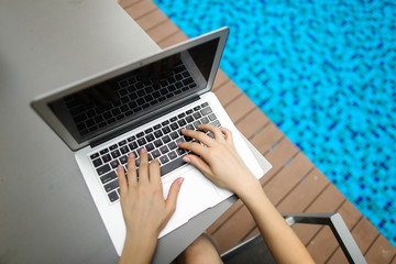 Wall Mural - view from above woman fingers pressing keyboard on laptop sunny