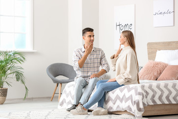 Wall Mural - Young deaf mute couple using sign language at home