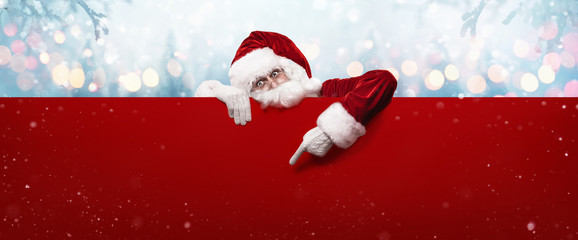 santa claus showing something on a red wall