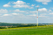 Windkraftanlage mit grüner Wiese und blauem Himmel