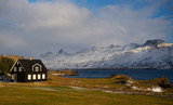 Fototapeta Sawanna - Traditional black house in Iceland by the fjord on the coast in winter