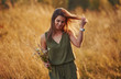 © standret - Beautful girl walks through the field with high grass and collecting flowers. Amazing sunlight