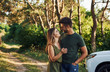 © standret - Standing near the white automobile. Beautiful young couple have a good time in the forest at daytime