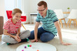 © spass - Happy young father plays with his teenager son Board Game with colorful dices