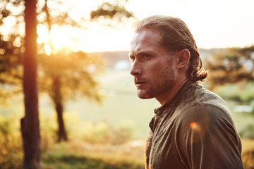 Beautiful man in the forest. Good weather. Beautiful orange colored sunlight