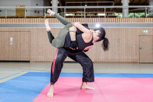 Female Kickboxer Practicing With Coach In Sports Hall