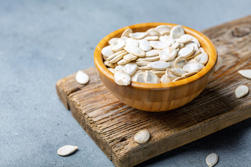 Wall Mural - Unpeeled pumpkin seeds in a wooden bowl.